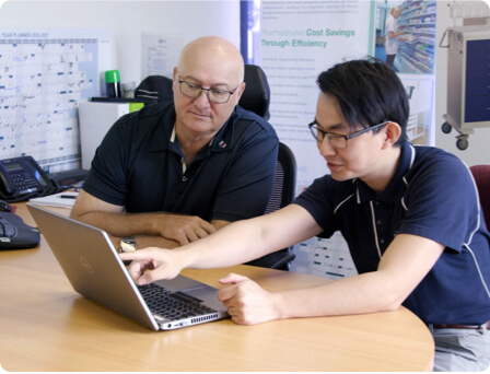 One of MGI's CFO advisory specialists Zee Zhang with a client, sitting at a desk pointing at a laptop screen