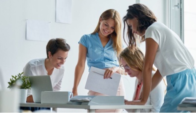 three business women gathered round a desk discussing a plan used on a blog post about a women in business grant