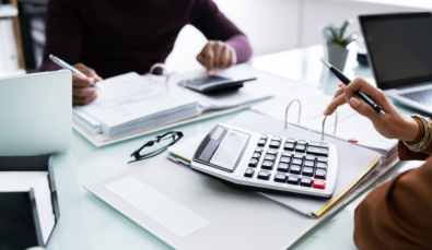 fingers typing on a large calculator on a file on a desk used on a blog about division 296 tax changes