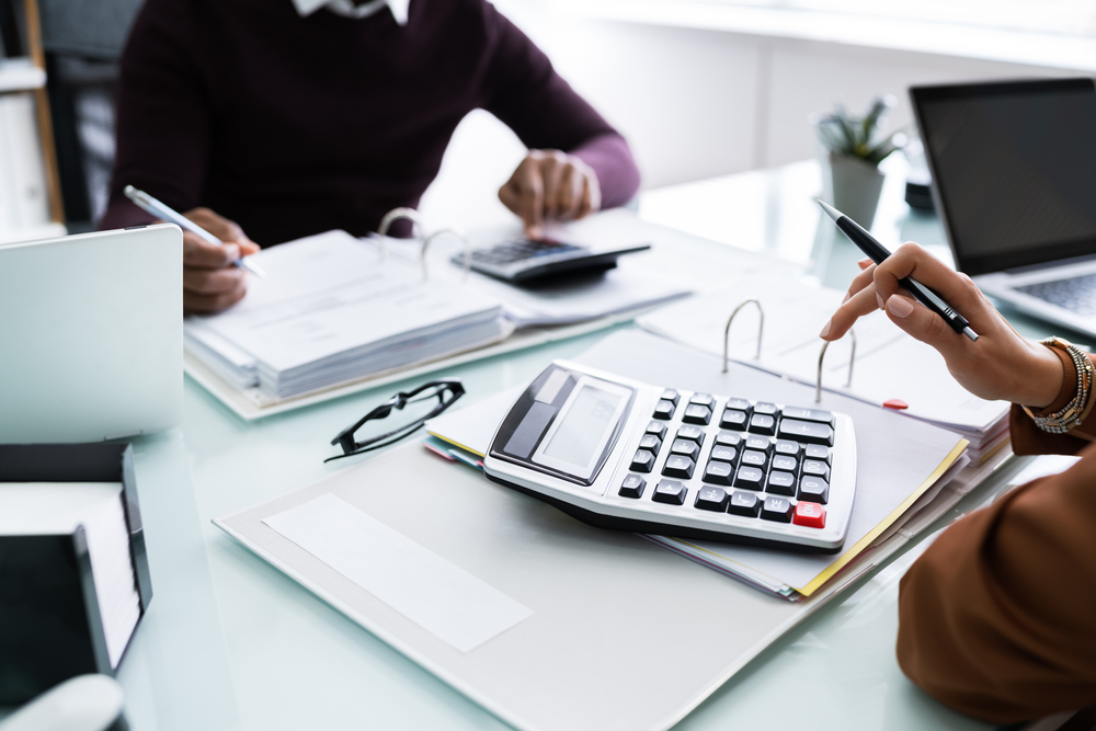 fingers typing on a large calculator on a file on a desk used on a blog about division 296 tax changes